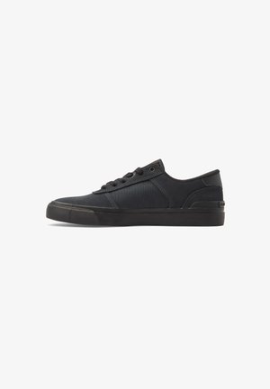 Sort lavtoppet sneakers med snørebånd foran, struktureret gummi sål og paneler i blandet stof og ruskind, vist i profil på hvid baggrund.