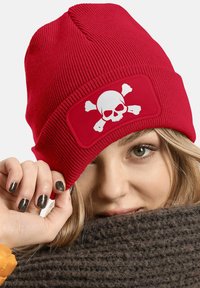 Red knitted beanie with a white skull and crossbones patch. The beanie features a ribbed texture and a snug fit.