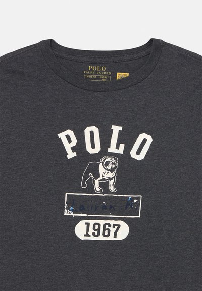 Tamno sivi pamučni majica s bijelim natpisom "POLO", ilustracijom buldoga i godinom "1967" u ovalnom dizajnu. Mekana tekstura i okrugli izrez.