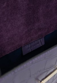 Borsa a mano in pelle viola genuina con una texture a motivo coccodrillo, dotata di un interno in morbido camoscio e dettagli in metallo dorato.