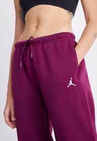 Bordeauxkleurige sweatpants met een tailleband met trekkoord, zijzakken en een wit Jumpman-logo op de linkerdij. Gemaakt van zachte stof met een relaxte pasvorm.