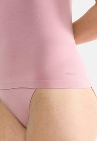 Top senza maniche di un delicato colore rosa chiaro, realizzato in tessuto morbido, con un design seamless e un sottile logo vicino all'orlo, abbinato a slip coordinati.