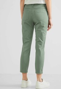 Zelené kalhoty z bavlněné směsi se střihovým střihem, zkrácenou délkou a designem s pěti kapsami. Dokončeno decentním šitím a páskem.