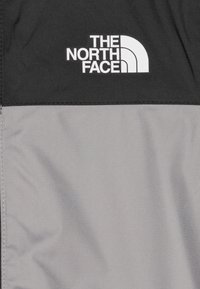 Schwarzer und grauer Nylonstoff mit einer glatten Textur; zeigt ein markantes weißes Logo von "The North Face" im oberen Bereich.
