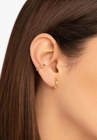 Orecchini a cerchio dorati con accenti di gioielli colorati; uno presenta un design dritto, mentre l'altro ha una forma ondulata.