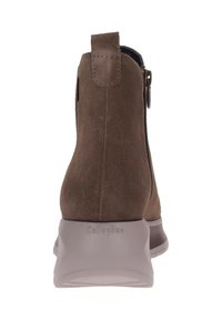 Stivale alla caviglia in suede marrone con cerniera laterale, colletto imbottito e suola in gomma grigia chiara. Presenta un logo sul tallone. Texture liscia.