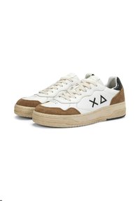 Sneakers bianchi a basso profilo con accenti in suede marrone, suole beige, linguetta nera sul tallone, lacci beige e simboli neri "X" e triangoli sui lati.