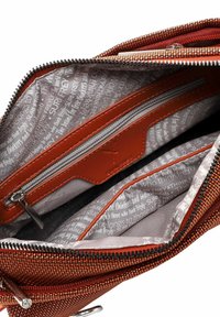 Interno di una borsa in tessuto arancione texturizzato con dettagli in pelle marrone, dotata di molteplici scomparti e una cerniera argentata. Foderata con tessuto a motivo.