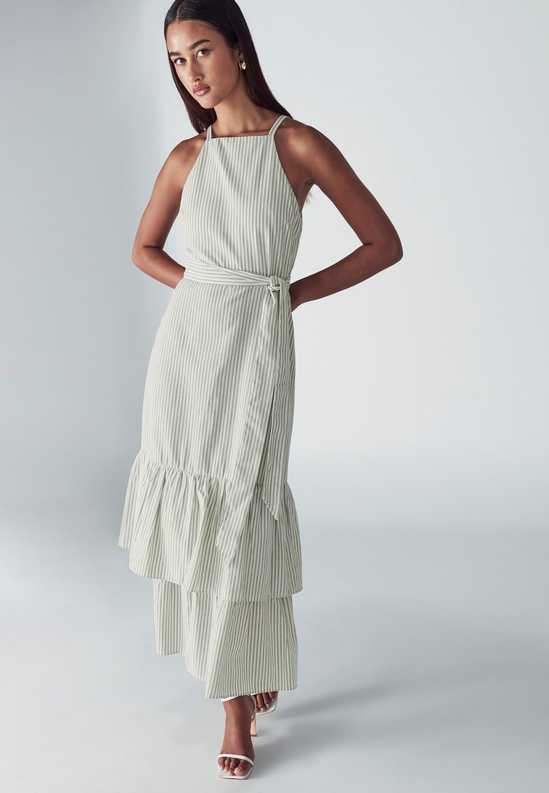 Juostuota, be rankovių suknelė šviesiai žaliai ir balta spalvomis, su rauktu, sluoksniuotu sijonu ir surišta juosmens detale. Lygi medžiaga, laisvas dizainas.