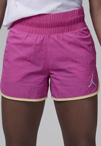 Shorts sportivi rosa con finitura testurizzata, vita elasticizzata e bordi gialli. Presentano un piccolo logo grigio di Jordan sul lato.