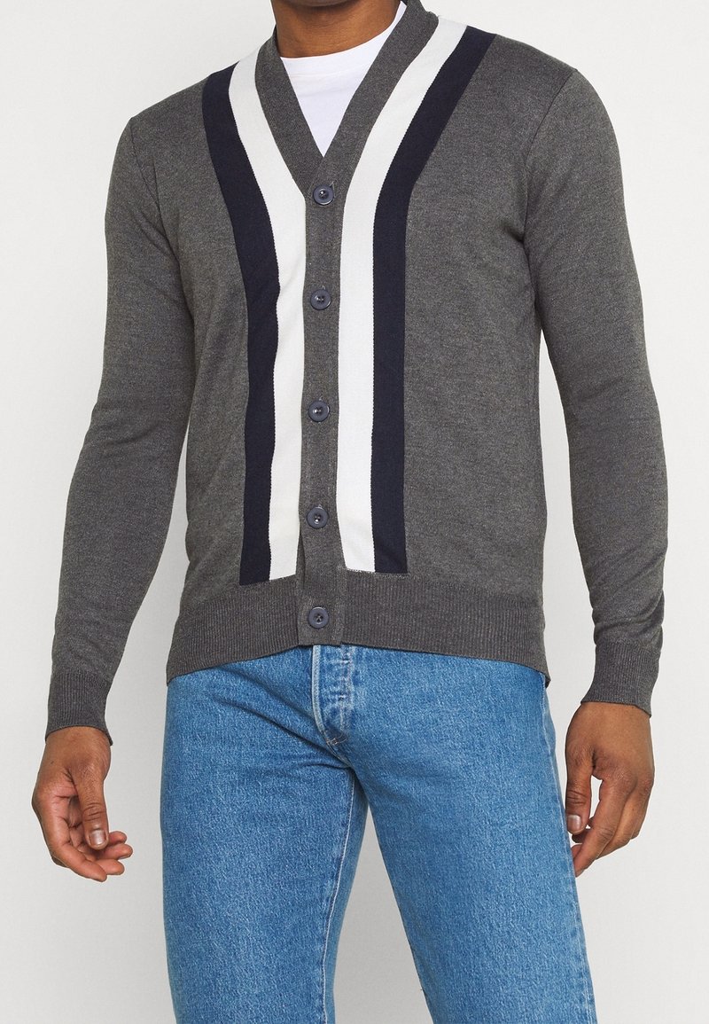 Grå cardigan med V-ringning, med vita och marinblå vertikala ränder. Stickat tyg, femknappslåsning, ribbade ärmslut och nederkant.
