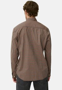 Braun-schwarz kariertes Langarmhemd, mit Knöpfen am Kragen und sichtbaren Nahtdetails, getragen mit grauen Jeans. Rückansicht.