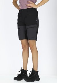 Svarta flerfickade shorts med en grå panel, tillverkade av lätt material. Har dragkedjor och en reflekterande logotyp på låret.