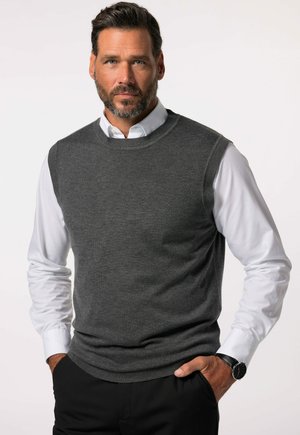 Grauer ärmelloser Pullover aus weichem Strickstoff, mit Rundhalsausschnitt und geripptem Saum, getragen über einem weißen Hemd mit Kragen. Schwarze Armbanduhr sichtbar.