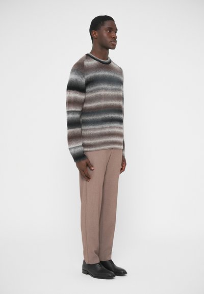 Πλεκτό πουλόβερ με οριζόντιες ρίγες σε καφέ, γκρι και μαύρο. Συνδυασμένο με μπεζ παντελόνια και μαύρα παπούτσια. Απλός σχεδιασμός με στρογγυλή λαιμόκοψη.