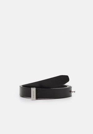 Ceinture en cuir noir enroulée horizontalement avec une boucle rectangulaire argentée gravée "Calvin Klein" sur fond blanc.