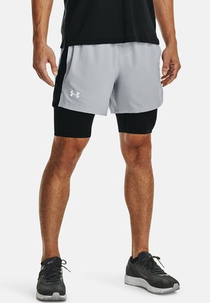 Sportshorts in lichtgrijs met zwarte accenten, gecombineerd met zwarte compressieshorts. Het materiaal is lichtgewicht en geschikt voor sportactiviteiten.