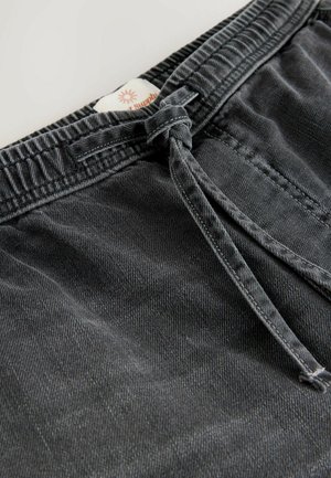 Sorte denimshorts med elastisk talje, der har et frontbånd, synlige sømme og et lille mærke nær taljen.