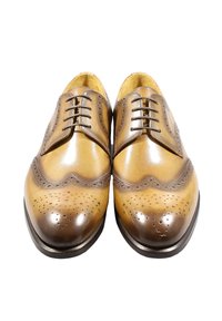 Scarpe Oxford in pelle marrone con dettagli traforati brogue, una finitura liscia e una punta leggermente più scura. I lacci sono posizionati centralmente.