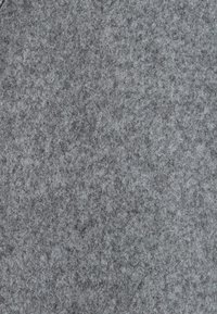 Tela de fieltro gris con una superficie suave y texturizada. El material parece denso y uniforme, presenta un patrón sutil y diferentes tonalidades de gris.