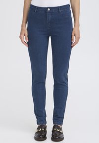 Jean en denim slim fit bleu foncé, avec une taille classique et un bouton en métal, poches avant et arrière, et texture lisse.