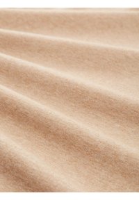 Tissu en coton beige avec une texture douce, présentant une légère élasticité et un léger brillant, exposé en douces plis et vagues.