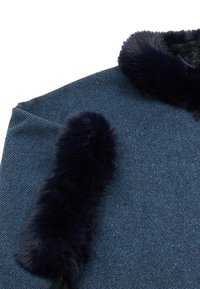 Sötétkék anyag textúrázott mintával, műszőrme díszítéssel a galléron és az ujjakon, kontrasztot és meleget adva.