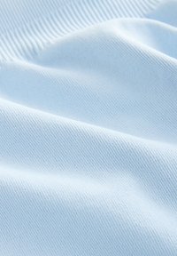 Lyseblåt stof med en glat tekstur, der viser fine ribbede detaljer og bløde folder, som indikerer blødhed og elasticitet.