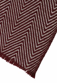 Burgundy and white zigzag-patterned woven textile, featuring fringed edges and a textured finish.
