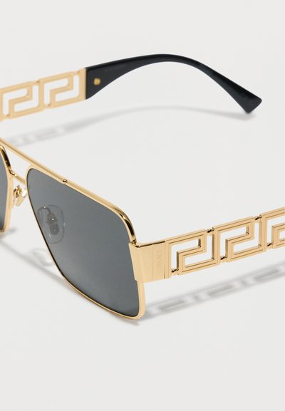 Γυαλιά ηλίου με χρυσή κορνίζα και μαύρους φακούς, με μοτίβο ελληνικού κλειδιού στα μπράτσα και μαύρες άκρες στους βραχίονες.