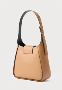 Tanni nahast käekott tugeva vormiga, lai must rihm ja eesmine klapp. Omab vähe õmblusi ja diskreetset brändingut.