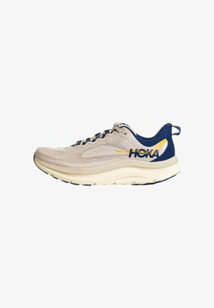 Scarpa da corsa beige chiaro e blu navy con suola spessa e logo "HOKA" sul lato, progettata per comfort e supporto.