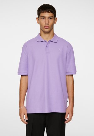 Polo shirt viola con uno scollo a tre bottoni, maniche corte e logo ricamato sul lato sinistro del petto, realizzato in tessuto morbido e textured.