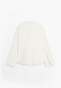 Chemise blanche à manches longues avec un col droit, vue de dos, présentant des lignes épurées et un ourlet légèrement courbé.