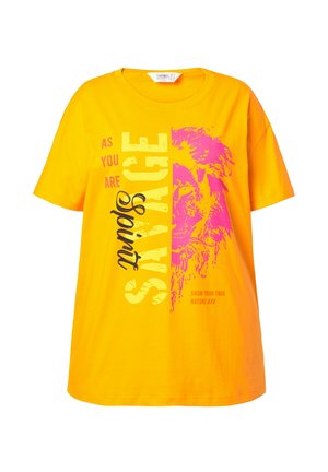 Helles gelbes T-Shirt mit pinkem Löwen-Graphic und dem Text "Sei, wie du bist, sprich" und "Zeige deine wahre Natur" auf der Vorderseite.