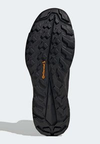 Semelle de chaussure en caoutchouc noir avec un motif de bande de roulement multidirectionnel, featuring des crampons hexagonaux et triangulaires surélevés pour une traction, et logo "Continental".