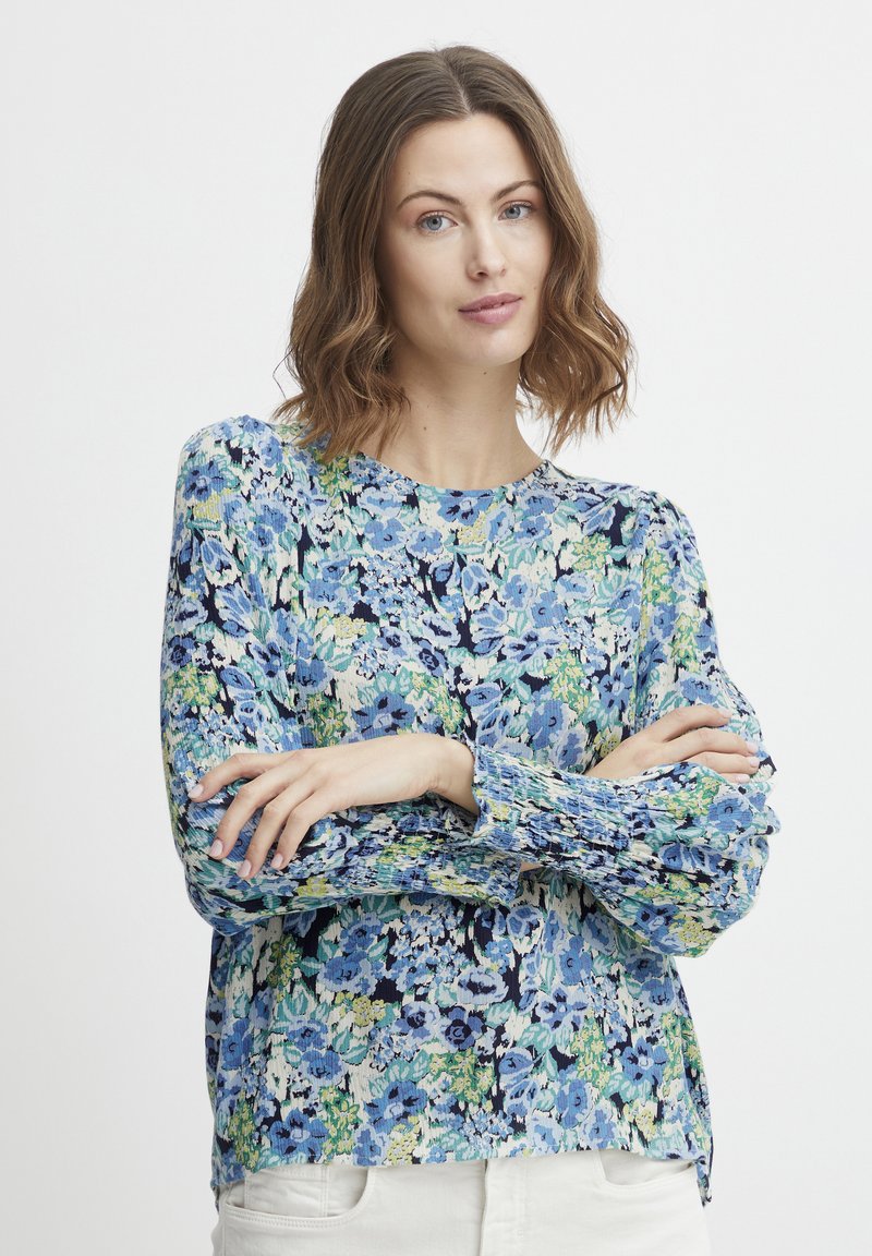 Blumenshirt mit einem blau-grünen Muster. Leichter Stoff, lange Ärmel mit gerafften Bündchen und rundem Halsausschnitt.