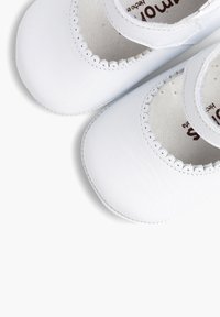 Witte leren babyschoenen met gegolfde randen en een ronde neus. Inclusief een band voor een stevige pasvorm, met een soepele textuur.