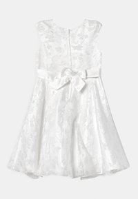 Vit klänning med blommig jacquardmönster, ärmlös design och satinsjörp med en rosett. Dold dragkedja i ryggen.