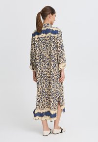 Leopardenmuster langes Kleid aus weichem Stoff, mit navyblauem Besatz, lockerer Passform und seitlichen Schlitzten für mehr Bewegungsfreiheit.