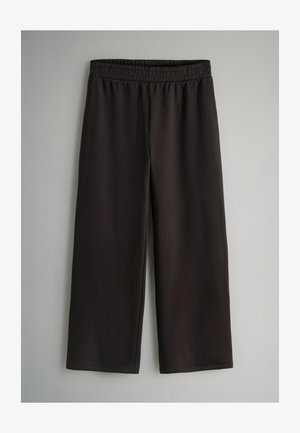 Schwarze Capri-Hosen aus glattem, elastischem Stoff mit einem elastischen Bund, die eine lockere Passform und weite Beine haben, ohne sichtbare Verschlüsse.