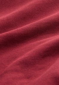 Bordeaux stof met een gladde textuur, voorzien van een ribbelpatroon en subtiele glans, met zachte draping en zachte vouwen.