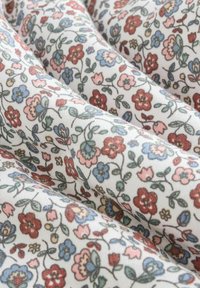 Kangas bercorak bunga dengan latar belakang putih yang dihiasi bunga berwarna merah, pink, biru, dan hijau, dengan tekstur yang lembut dan kilau yang halus.