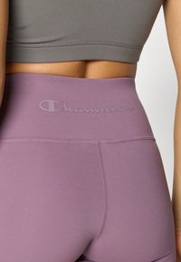 Μακριά μωβ κολάν με ψηλή μέση και ελαστική ζώνη μέσης, με μονοχρωμικό λογότυπο «Champion». Ομαλό, ελαστικό ύφασμα με επίπεδες ραφές.
