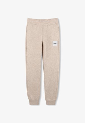 Beige joggingbroek met elastische tailleband en boorden, zijzakken en een witte vierkante patch met de tekst "BOSS" op het bovenste gedeelte van het linkerbeen.