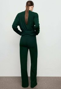 Su�éter de punto verde oscuro y pantalones de pierna ancha a juego, con mangas largas, un ajuste relajado y una textura suave.