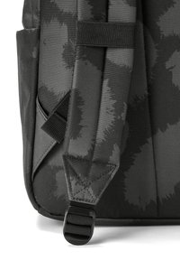 Detailné zobrazenie čierneho látkového batohu s textúrovaným vzorom, nastaviteľnými popruhmi a plastovými prvkami na pripevnenie.