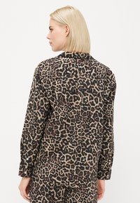 Leopardmønstret skjorte i blødt stof, med krave, lange ærmer og knaplige manchetter. Teksturen er glat med en afslappet pasform.