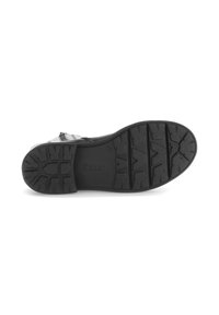 Zwarte rubberen zool van een schoen met diepe profielgroeven en ingedrukte merknaam. Heeft een gestructureerd patroon voor grip en duurzaamheid.