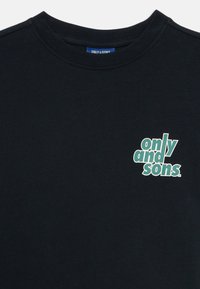 Svart crewneck t-shirt med en liten grön och vit "only and sons"-logotyp på vänster bröst och en blå nacktag.